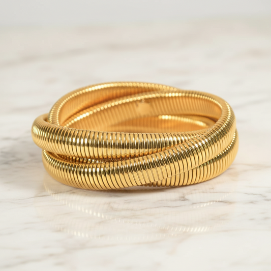 Two gold bangles stacked on a light beige background with 'godazzle' branding.
